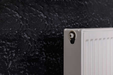 Modern radiator on black wall, space for text. central heating systemの写真素材