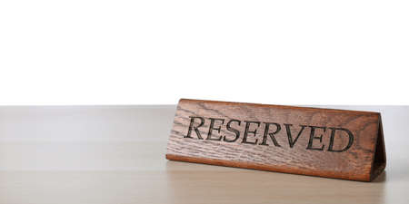 Elegant wooden sign Reserved on table against white background, space for textの写真素材