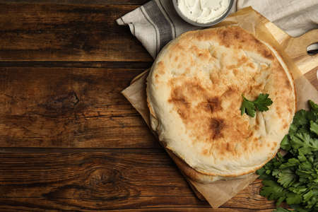 Loaves of delicious homemade pita bread, cream cheese and parsley on wooden table, flat lay. Space for textの写真素材