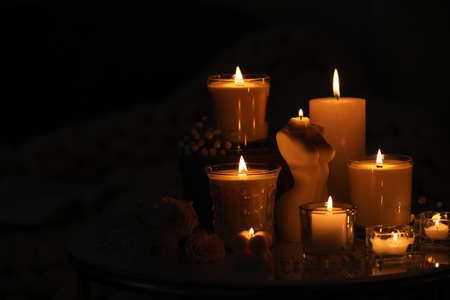 Beautiful burning candles on table in darkness. Space for textの写真素材