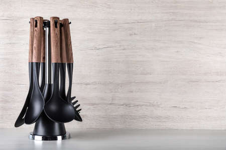 Holder with different kitchen utensils on white wooden table. Space for text