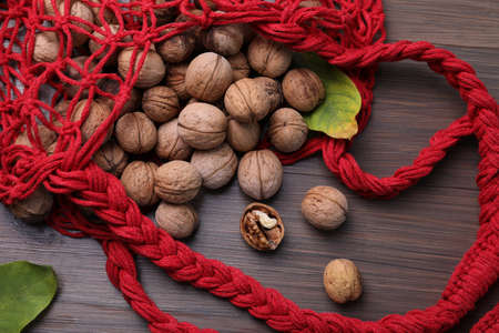 Net bag with walnuts and fresh leaves on wooden table, flat layの写真素材