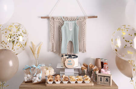 baby shower party. Different delicious treats on wooden table and decor near light wallの写真素材