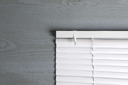 Stylish horizontal window blinds on gray wooden table, top view. Space for textの写真素材