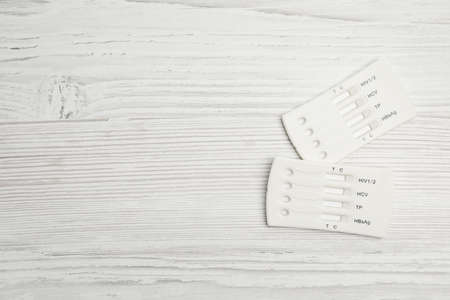 Two disposable express hepatitis tests on white wooden table, flat lay. Space for text