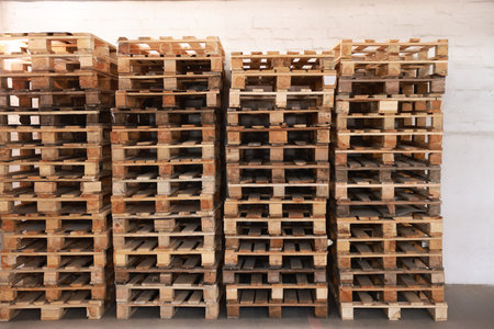 Many empty wooden pallets stacked in warehouse