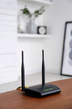 Modern WiFi router on wooden table indoors