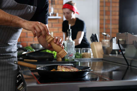 Professional chef cooking meat on stove in restaurant kitchen, closeupの写真素材