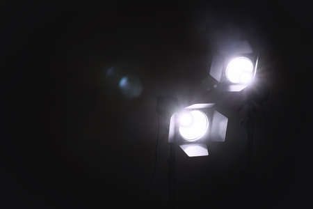 Bright white spotlights in darkness, space for text