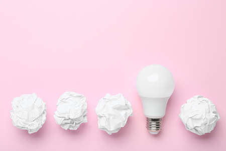 Creative flat lay composition with lightbulb and paper balls on pink background, space for text....