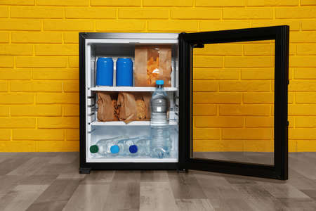 Mini bar filled with food and drinks near yellow brick wall indoorsの写真素材