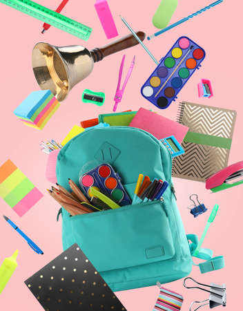 Turquoise backpack, school bell and different stationery flying on pink background