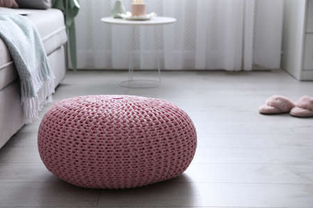 Pink knitted pouf near sofa in living room. Space for textの写真素材