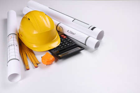 Construction drawings, safety hat, calculator, tape measure and folding ruler on white background....