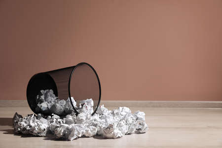 Overturned trash with paper on floor near pale pink wall, space for text. Recycling rubbishの写真素材