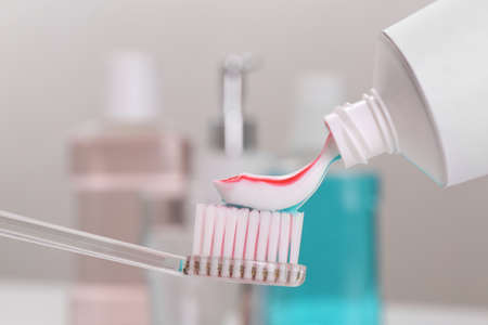 Applying paste on toothbrush near mouthwash, closeup