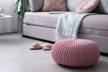 Pink knitted pouf near sofa in living room. Space for textの写真素材