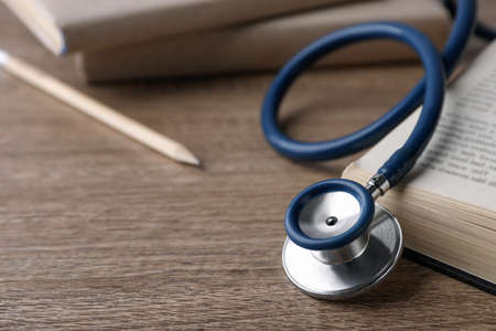 Student textbook and stethoscope on wooden table, closeup view with space for text . medical educationの写真素材