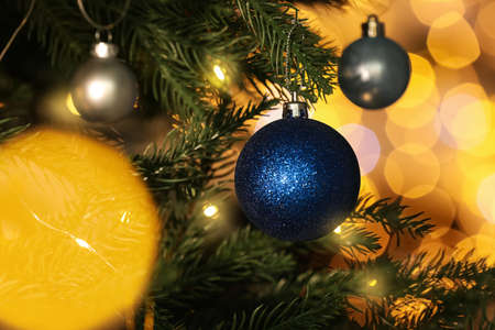 Beautiful shiny holiday baubles hanging on Christmas tree against blurred fairy lights, closeupの写真素材