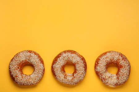 Delicious fresh bagels with sesame seeds on orange background, flat lay. Space for textの写真素材