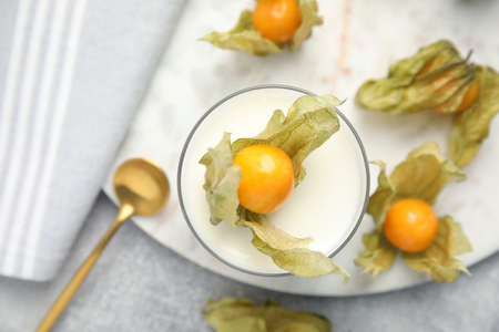 Delicious dessert decorated with physalis fruit on light gray table, flat lay