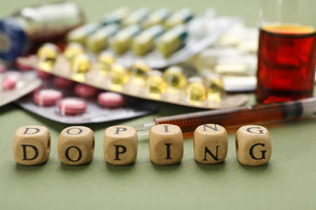 Wooden cubes with word Doping and drugs on green background, closeupの写真素材
