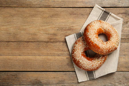Delicious fresh bagels with sesame seeds on wooden table, top view. Space for text