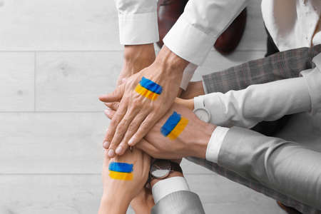 United for Ukraine. People holding hands with drawings of Ukrainian flag together, closeup
