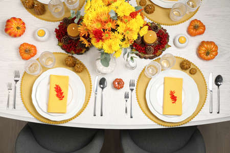 Autumn table setting with floral decor and pumpkins indoors, top view