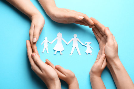 Parents and child protecting paper cutout of family on light blue background, top viewの写真素材