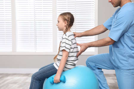 Orthopedist helping child to do exercise with dumbbell in clinic, closeup. scoliosis treatmentの写真素材