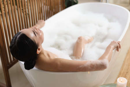 Beautiful young woman taking bubble bath at homeの写真素材