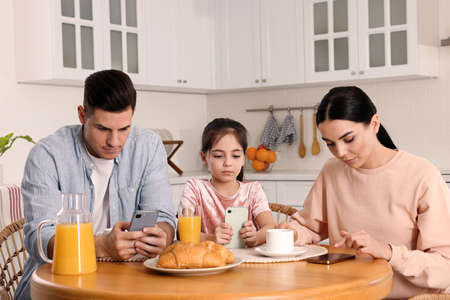 internet addiction. Family with smartphones at table in kitchenの写真素材