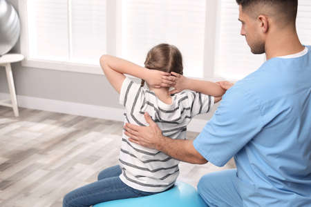Orthopedist helping child to do exercise in clinic. scoliosis treatment