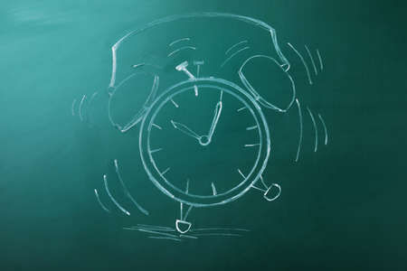 Drawn alarm clock on green chalkboard. school time