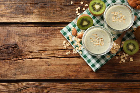 Flat lay composition with tasty kiwi oatmeal smoothie on wooden table. Space for textの写真素材