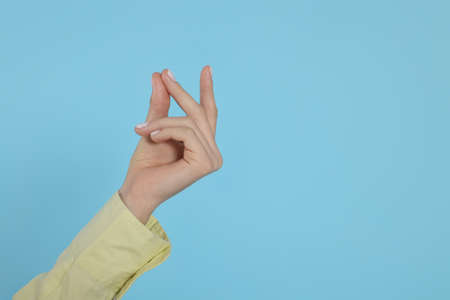 Woman snapping fingers on light blue background, closeup of hand. Space for textの写真素材