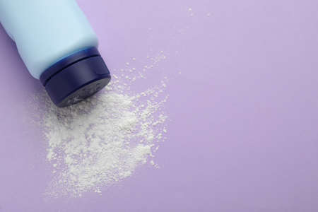 Bottle and scattered dusting powder on lilac background, top view with space for text. baby cosmetic productの写真素材