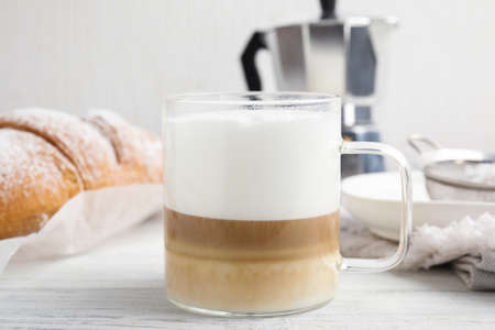 Delicious latte macchiato and croissant on white wooden tableの写真素材
