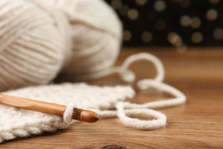 Knitting and crochet hook on wooden table against blurred lights, closeup. Space for textの写真素材