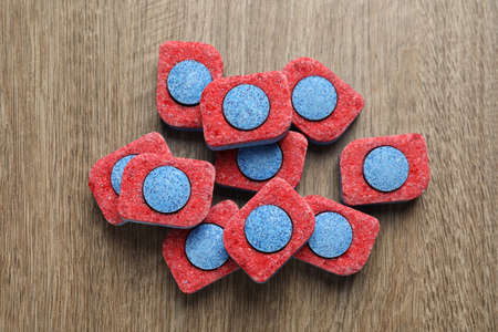Many dishwasher detergent tablets on wooden table, flat lay