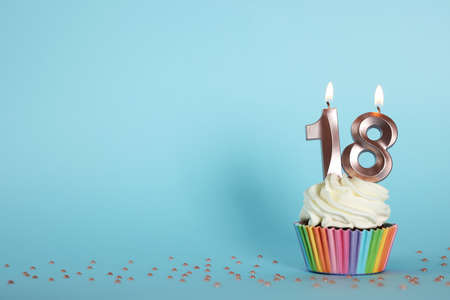 Delicious cupcake with number shaped candles on light blue background, space for text. Coming of age...