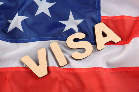 Word Visa made of wooden letters on American flag, flat lay. Immigration to USAの写真素材
