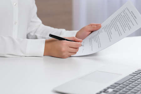 Businesswoman signing contract at white table in office, closeup of hands