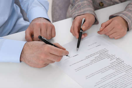 Businesspeople signing contract at white table, closeup of handsの写真素材