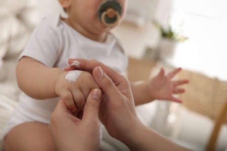 Mother applying body cream on her little baby at home, closeupの写真素材
