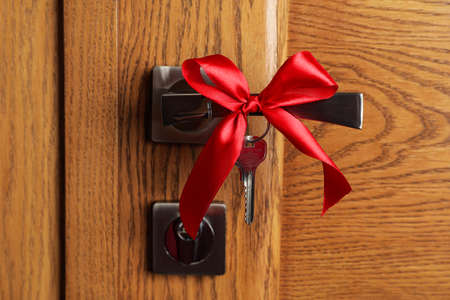 Key with red bow on door handle, closeup view. house warming partyの写真素材