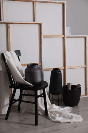 Chair with white fabric and vase near paintings in artist's studio