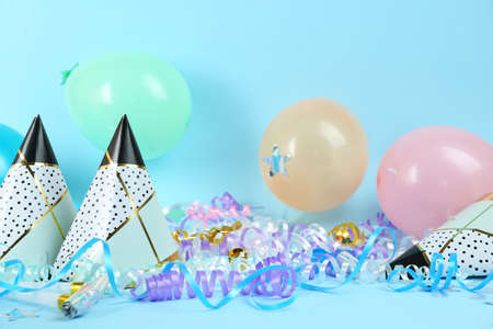 Colorful serpentine streamers, caps, party horns and balloons on light blue backgroundの写真素材