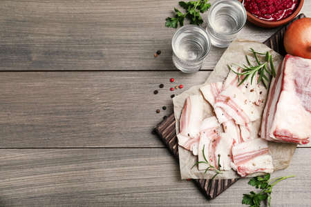 Tasty salt pork with rosemary and spices on wooden table, flat lay. Space for textの写真素材